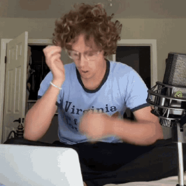 a man in a virginia shirt is sitting in front of a laptop
