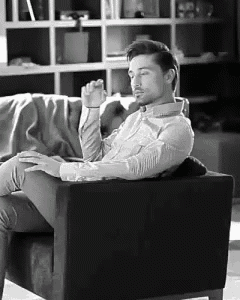 a man is sitting in a chair in front of a bookshelf .