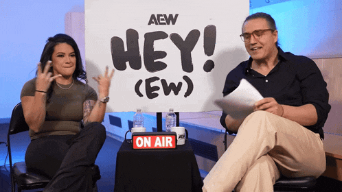 two people are sitting in front of a sign that says hey ( ew )