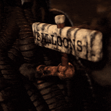 a sign that says " balloons " is hanging from a rope