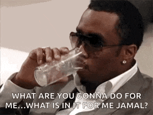 a man in a suit and sunglasses is drinking a glass of water and asking what are you gonna do for me .