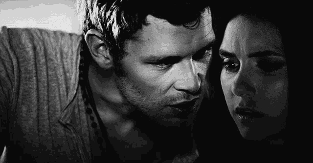 a black and white photo of a man and a woman looking into each other 's eyes .