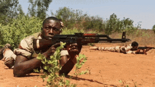 a man laying on the ground with a rifle in his hand