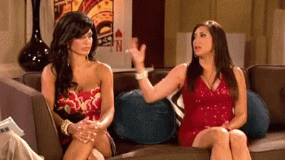 two women are sitting on a couch having a conversation .