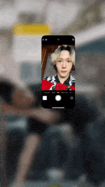 a phone screen shows a person taking a selfie with a red shirt on