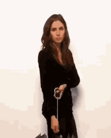a woman in a black dress is holding an umbrella in her hand .