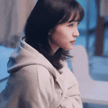 a close up of a woman wearing a hoodie looking at something