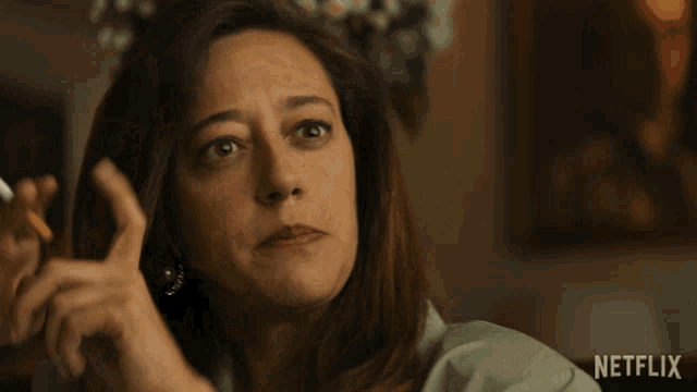 a woman with a ring on her finger smoking a cigarette and says " a ver te escucho "