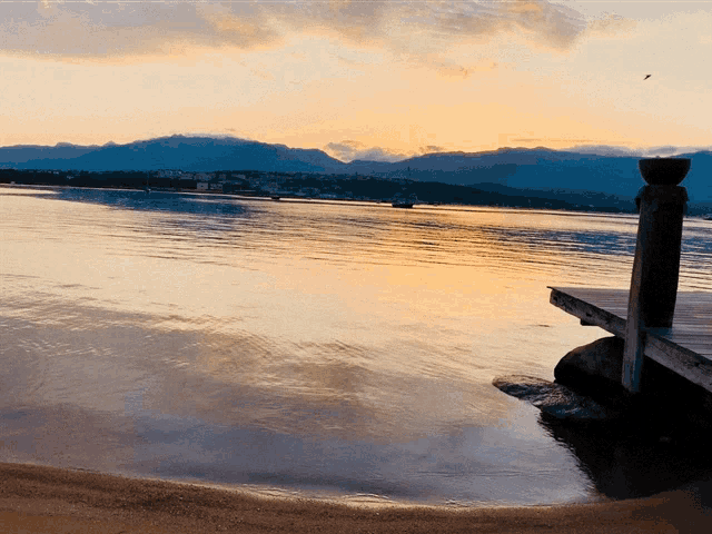 a sunset over a body of water with a dock in the foreground