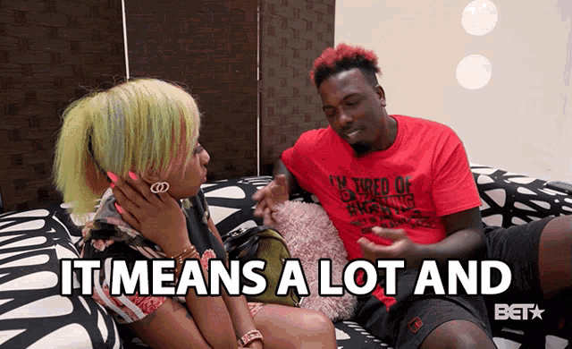 a man and woman are sitting on a couch and the man is wearing a red shirt that says " tired of everything "