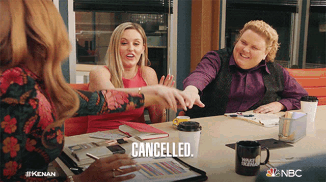 a group of people sitting around a table with the word cancelled written on it