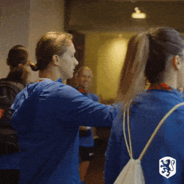a woman wearing a blue jacket with a lion on the back