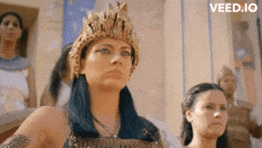 a woman with a crown on her head is standing in front of a group of women .