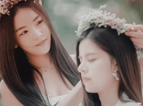 a woman wearing a flower crown on her head next to another woman wearing a flower crown