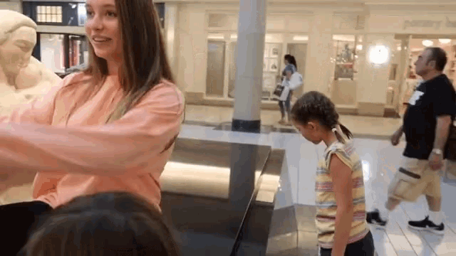 a woman in a pink shirt is talking to a girl in a yellow striped shirt