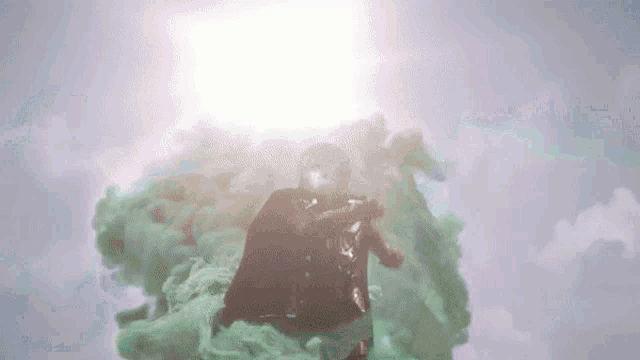 a man in a superhero costume is flying through a cloud of green smoke