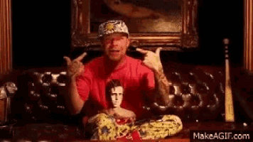 a man in a red shirt is sitting on a couch holding a doll