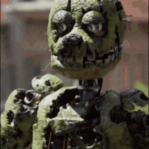 a close up of a green monster with a snake in its mouth .