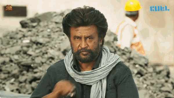 a man wearing a scarf and a hard hat stands in front of a pile of rocks