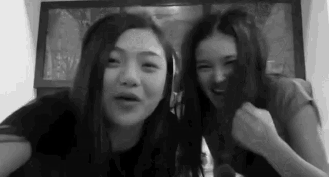 a black and white photo of two young women standing next to each other and laughing .