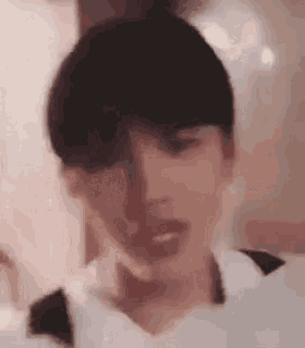 a close up of a person 's face with a blurred background holding a piece of paper .