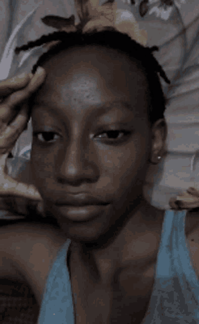 a close up of a person 's face with a blue tank top on