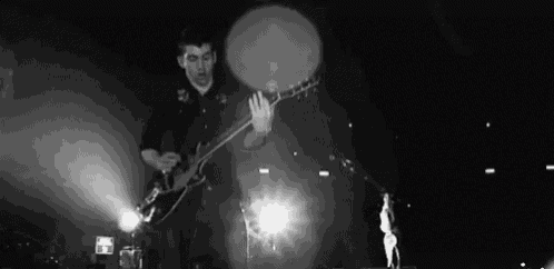 a man is playing a guitar on a stage in front of a microphone .