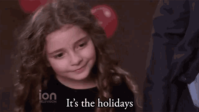 a little girl says it 's the holidays in front of a balloon
