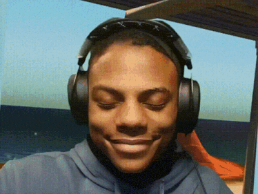 a man wearing headphones with his eyes closed smiles