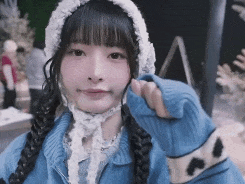 a girl wearing a blue sweater and a white hat is making a face .