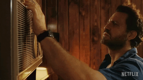 a man in a blue shirt is adjusting an air conditioner with a netflix logo in the corner