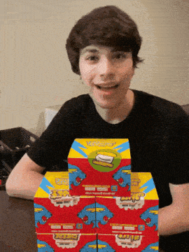 a young man is holding a stack of boxes with a picture of a burger on them