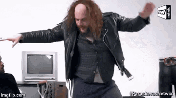 a man in a leather jacket is dancing in front of a tv with the words paraskevas netwix on the bottom