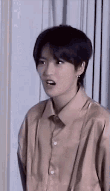 a young woman is making a funny face while wearing a brown shirt .
