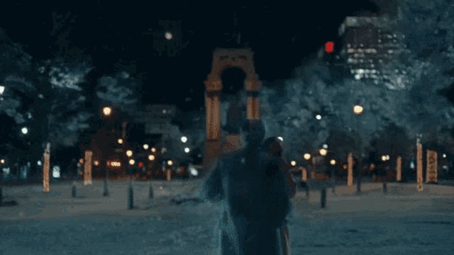 a man and woman are hugging in the snow in front of a city