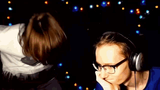a man wearing headphones and glasses is laying on a bed next to a woman .
