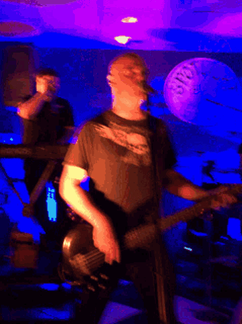 a blurry image of a man playing a guitar in a dark room
