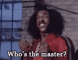 a man with curly hair is holding his fist in the air and saying `` who 's the master '' .