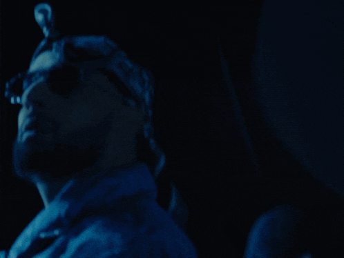 a man in a bandana is standing in the dark