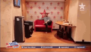 a man sits on a red couch in front of a wall with stars