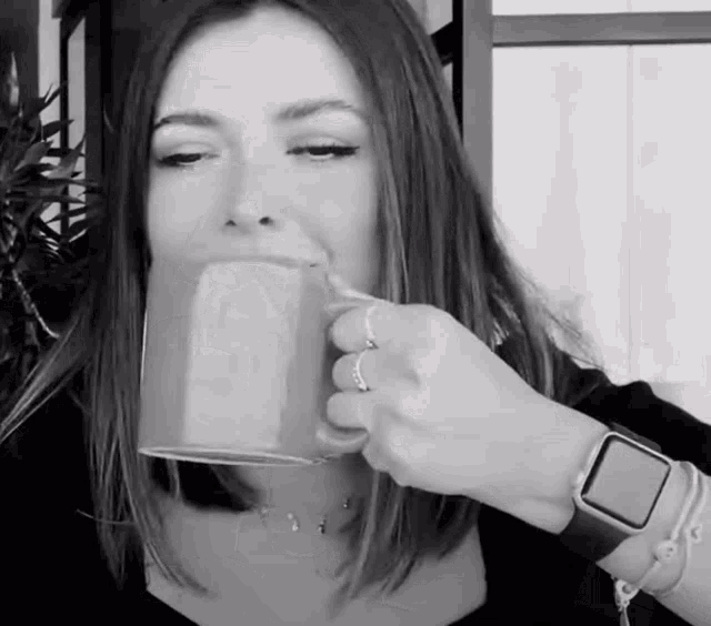 a woman drinking a cup of coffee with a watch on