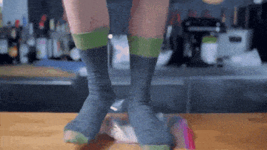 a person wearing a pair of gray and green socks stands on a table
