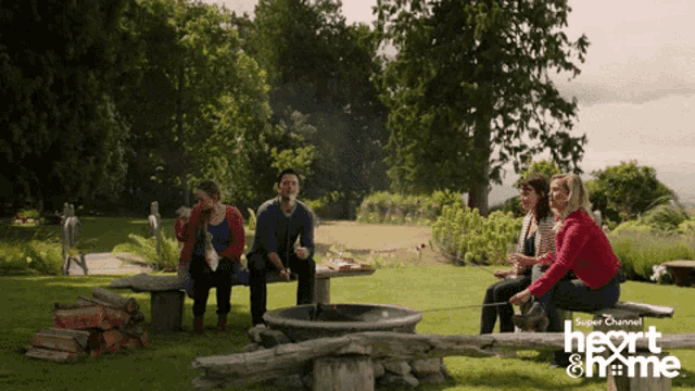 a group of people are sitting around a fire pit sponsored by super channel