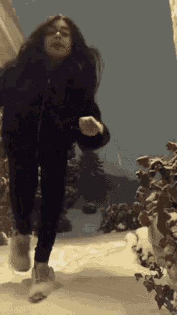 a girl in a black jacket is running through the snow