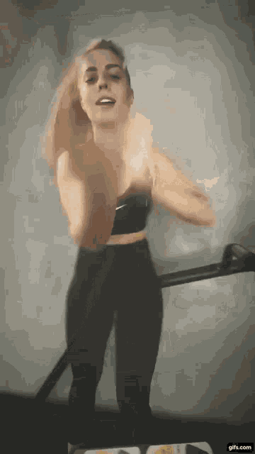 a woman is dancing on a treadmill in a gym .