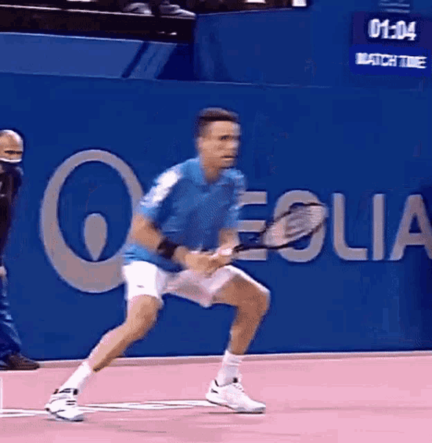 a man in a blue shirt is holding a tennis racquet in front of a sign that says " eolia "