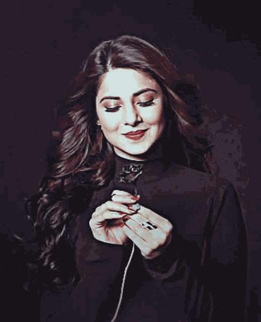 a woman in a black dress is smiling and holding something in her hand