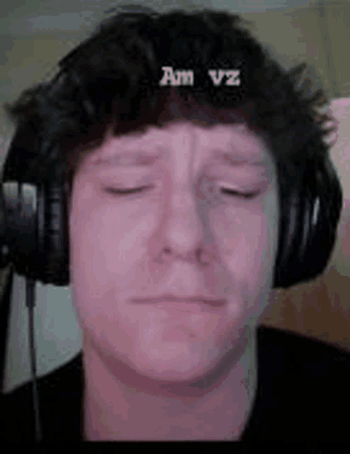 a man wearing headphones with his eyes closed is making a sad face .