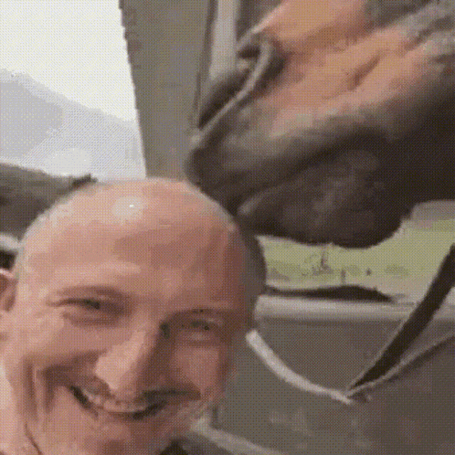 a bald man is smiling while a horse licks his head .