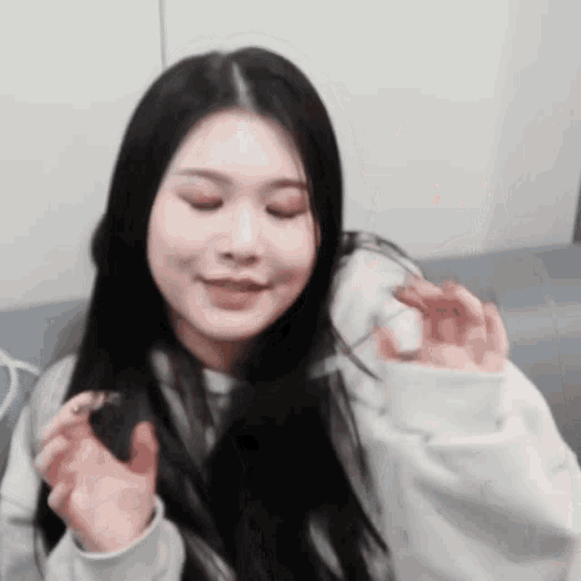 a woman with long black hair is sitting on a couch making a funny face